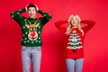 Photo of amazed surprised funny couple omg reaction wear ugly sweater jeans shoes isolated red color background