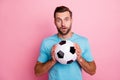 Photo of amazed surprised man in stupor holding soccer ball with hands loving to play football isolated pastel color