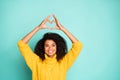 Photo of amazing dark skin lady holding hands in heart figure above head symbolizing cardiac health wear yellow knitted Royalty Free Stock Photo