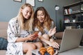 Cheerful positive women at home using laptop computer and mobile phone Royalty Free Stock Photo