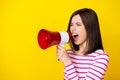 Photo of angry aggressive screaming woman striped shirt shouting in loudspeaker look at empty space isolated on yellow
