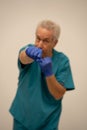 Photo of an angry doctor punching fist with blue gloves