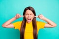 Photo of angry girl close cover ears with index finger yell loud wear yellow t-shirt isolated over turquoise color