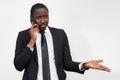 Closeup of angry young african man screaming while talking on smartphone over grey background Royalty Free Stock Photo