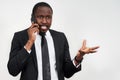Closeup of angry young african man screaming while talking on smartphone over grey background Royalty Free Stock Photo