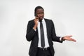 Closeup of angry young african man screaming while talking on smartphone over grey background Royalty Free Stock Photo