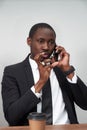 Closeup of angry young african man screaming while talking on smartphone over grey background Royalty Free Stock Photo