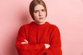 Photo of annoyed blonde woman in red sweater posing with hands crossed