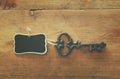 photo of antique key and empty blackboard tag over old wooden table. Royalty Free Stock Photo