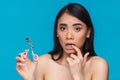 Confused young woman holding eyelash curler