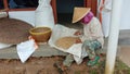 Photo of an Asian farmer sorting rice in front of a wooden house