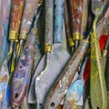 Assortment of dirty artist`s tools laying on studio bench splattered in oil paint