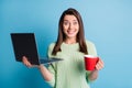 Photo of astonished girl hold laptop cappuccino cup wear green sweater isolated over blue color background Royalty Free Stock Photo