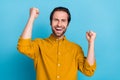 Photo of astonished guy raise hands celebrate triumph victory wear yellow shirt isolated blue color background