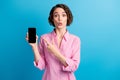 Photo of astonished lady point index finger smart phone isolated over blue pastel color background