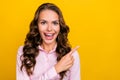 Photo of astonished millennial brunette lady indicate empty space wear pink shirt isolated on yellow color background
