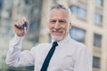 Photo of attentive good mood age businessman wear white shirt holding new apartment keys outside city street