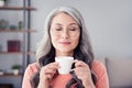 Photo of attractive aged woman happy positive smile enjoy morning hot coffee dream break pause indoors Royalty Free Stock Photo