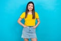 Photo of attractive asian girl model wear yellow t-shirt denim short skirt advertise clothes isolated blue teal color Royalty Free Stock Photo