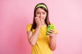 Photo of attractive beautiful frightened scared nervous girl bite fingers look smartphone isolated on pink color