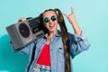 Photo of attractive beautiful woman dressed denim jacket dark glasses listening boom box showing rock sign isolated teal Royalty Free Stock Photo