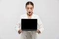 Photo of attractive businesswoman 20s wearing elegant jacket holding laptop and showing black screen Royalty Free Stock Photo