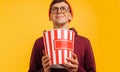 Attractive crazy man holding big bucket of popcorn, eating popcorn, laughing out loud, on yellow background Royalty Free Stock Photo
