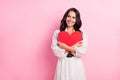 Photo of attractive dreamy young woman look empty space embrace red heart shape isolated on pastel pink color background