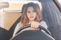 Photo of attractive female driver sits in car, teaches to drive, being inexperienced, has thoughtful expression. Woman in transpor