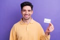 Photo of attractive good mood man dressed yellow shirt rising bank card isolated purple color background