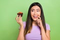 Photo of attractive japanese korean young woman muffin bite nail tempting wear trendy purple clothes isolated on green Royalty Free Stock Photo