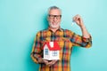 Photo of attractive man pensioner dressed checkered shirt glasses holding small house keys isolated teal color Royalty Free Stock Photo