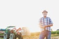 Attractive mature senior farmer standing against corn tractor in field Royalty Free Stock Photo