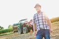 Attractive mature senior farmer standing against tractor in field Royalty Free Stock Photo