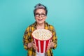 Photo of attractive retired woman bucket popcorn excited dressed stylish checkered yellow clothes isolated on aquamarine