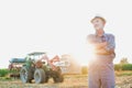 Attractive senior farmer standing against tractor in field Royalty Free Stock Photo