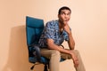 Photo of attractive suspicious man wear print shirt sitting office armchair arm chin looking empty space  beige Royalty Free Stock Photo