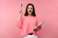 Photo of attractive woman in glasses holds book and pencil, looks quick-witted. Student got idea. Wear casual pink t