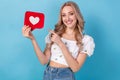 Photo of attractive young funny woman blonde wavy hair pointing finger paper follow heart advert isolated on blue color