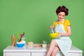 Photo of attractive young lady cooking cheerful sitting table improvisation kitchen curlers hair charming housewife wear