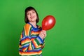 Photo of attractive young woman smile good mood hold hands red balloon isolated on green color background Royalty Free Stock Photo