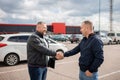 Photo of auto seller discussing with client about car model..People shaking hands with each other..Successful car sale-purchase