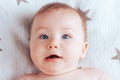 Photo of a baby with the emotion of surprise, a newborn baby with blue eyes and blond hair lying on a light blanket with Royalty Free Stock Photo