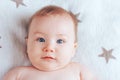 Photo of a baby with the emotion of surprise, a newborn baby with blue eyes and blond hair lying on a light blanket with brown Royalty Free Stock Photo