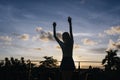 Photo from back of active slim woman posing with hands up in evening. Outdoor shot of graceful lady