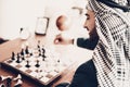 Photo from back as Arab playing chess at table