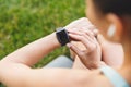 Photo from back closeup of brunette young woman 20s in sportswear resting in green park, and looking at wrist watch with Royalty Free Stock Photo