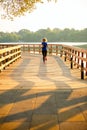 Photo from back of sports woman running on wooden bridge on summer.