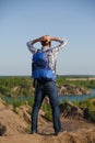 Photo back of tourist man with backpack with hands behind head on hill against backdrop of mountain expanses, blue sky