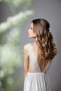 Photo from the back of a very beautiful young model in bridal dress with gypsophila flowers in her hands. Romantic style